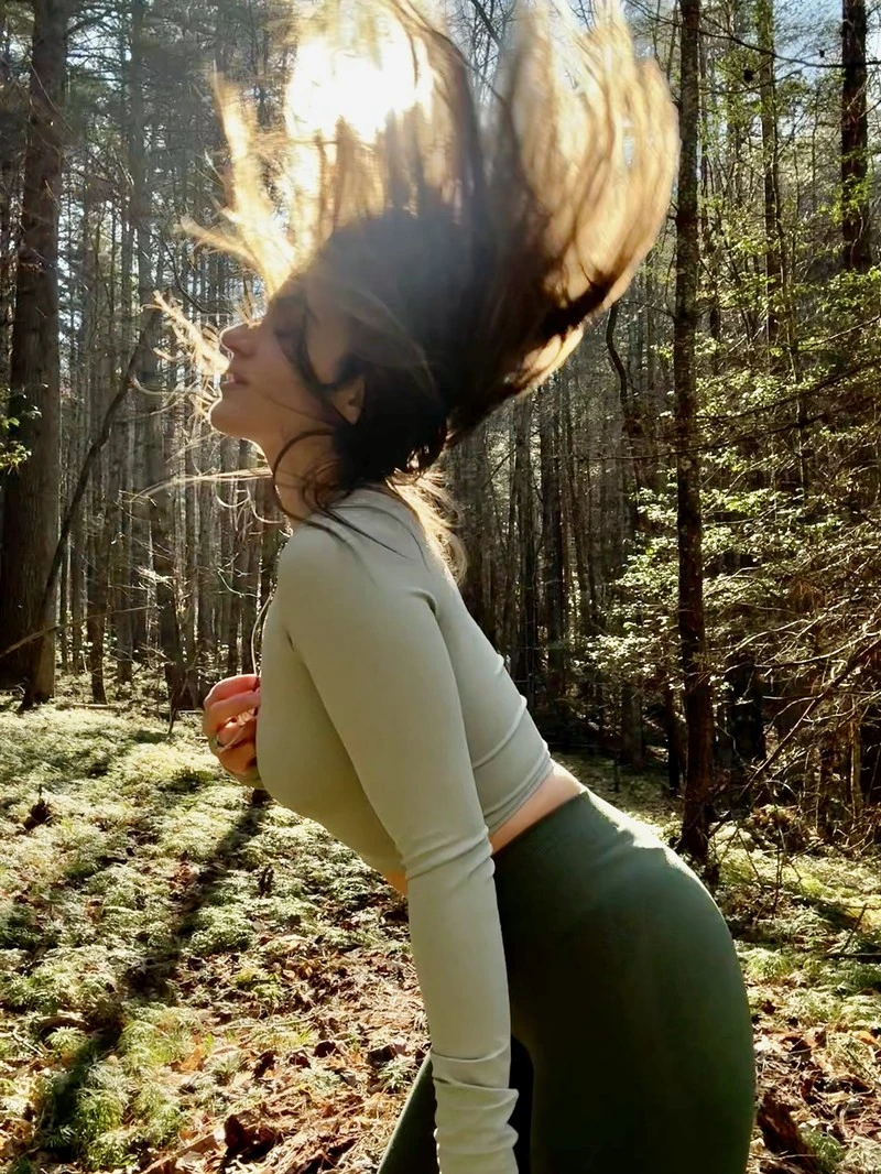 Lauren in a forest with her hair swept up in the sunlight